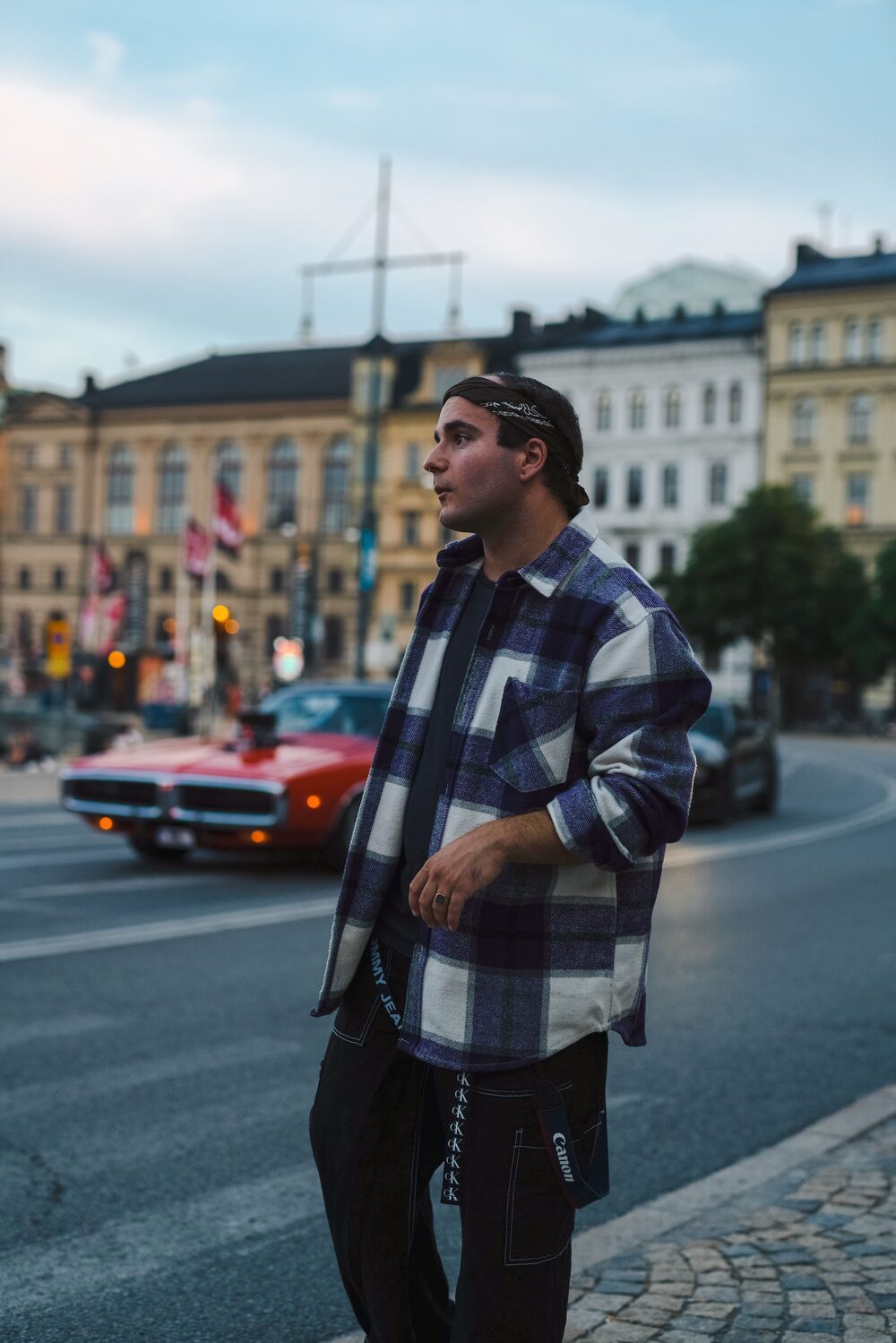Kapsułka lat 90' — oversizowa flanelowa koszula w kratkę na czarnym T-shircie i spodniach cargo, stylizacja inspirowana grunge i hip-hopem