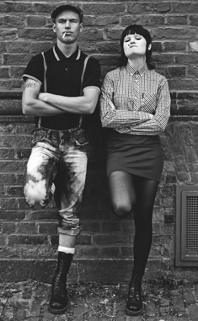 Skinheadzi — para w stylu skinhead: polo Fred Perry, szelki, podwinięte jeansy i glany